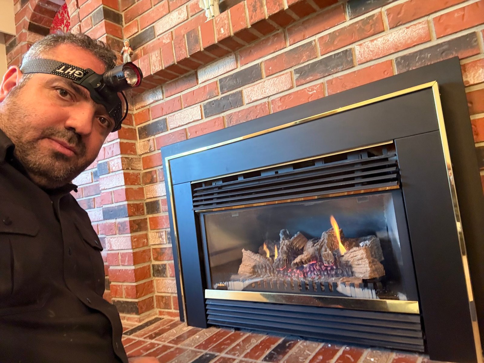 Daney from Efficient Fireplace Services working beside a gas fireplace